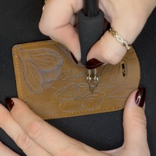 Hand engraving a custom leather business card holder with floral design and NFC tap-to-connect technology by Houston calligrapher and engraver Jessica Wofford.