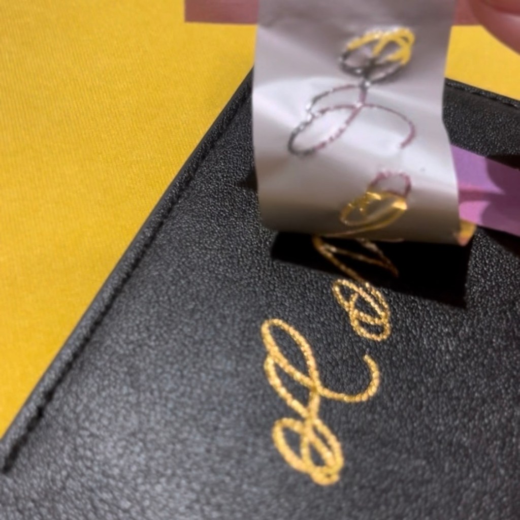 Peeling back heat-reactive tape to reveal gold foil lettering on a black PU leather luggage tag during a Nordstrom ICON member activation by Houston calligrapher and engraver Jessica Wofford.