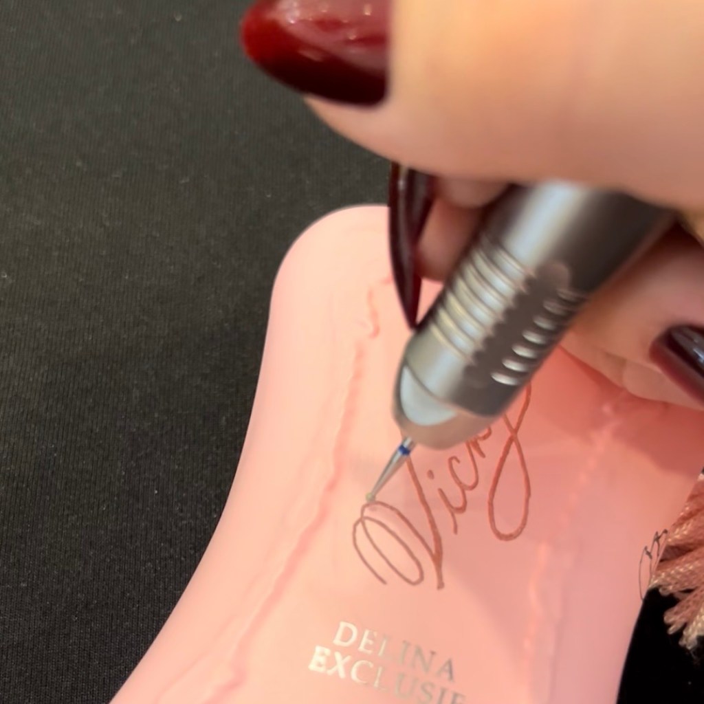 Hand engraving a Parfums de Marly pink fragrance bottle during a luxury brand activation featuring a company historian, personalized by Houston calligrapher and engraver Jessica Wofford.