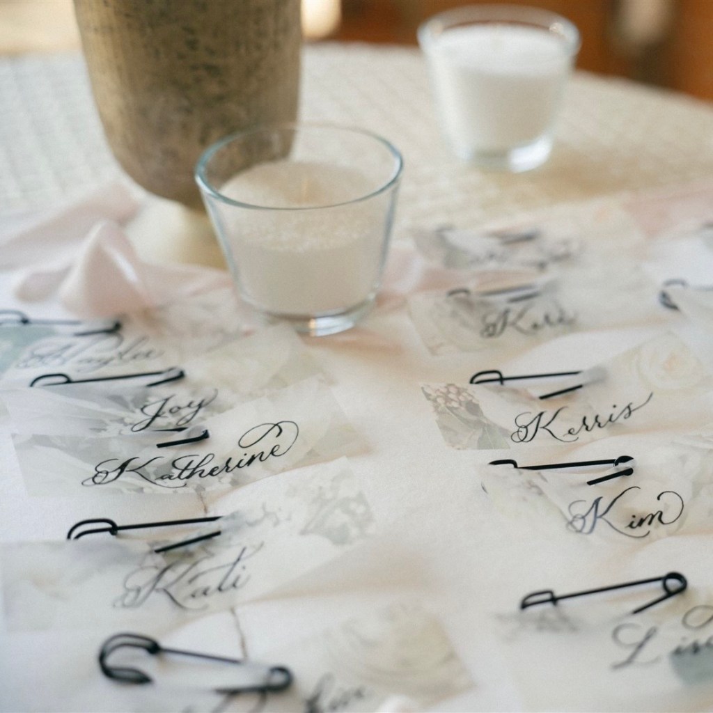 Elegant vellum name tags with dip pen calligraphy and industrial black clothespins for an escort card display at an industrial styled shoot.