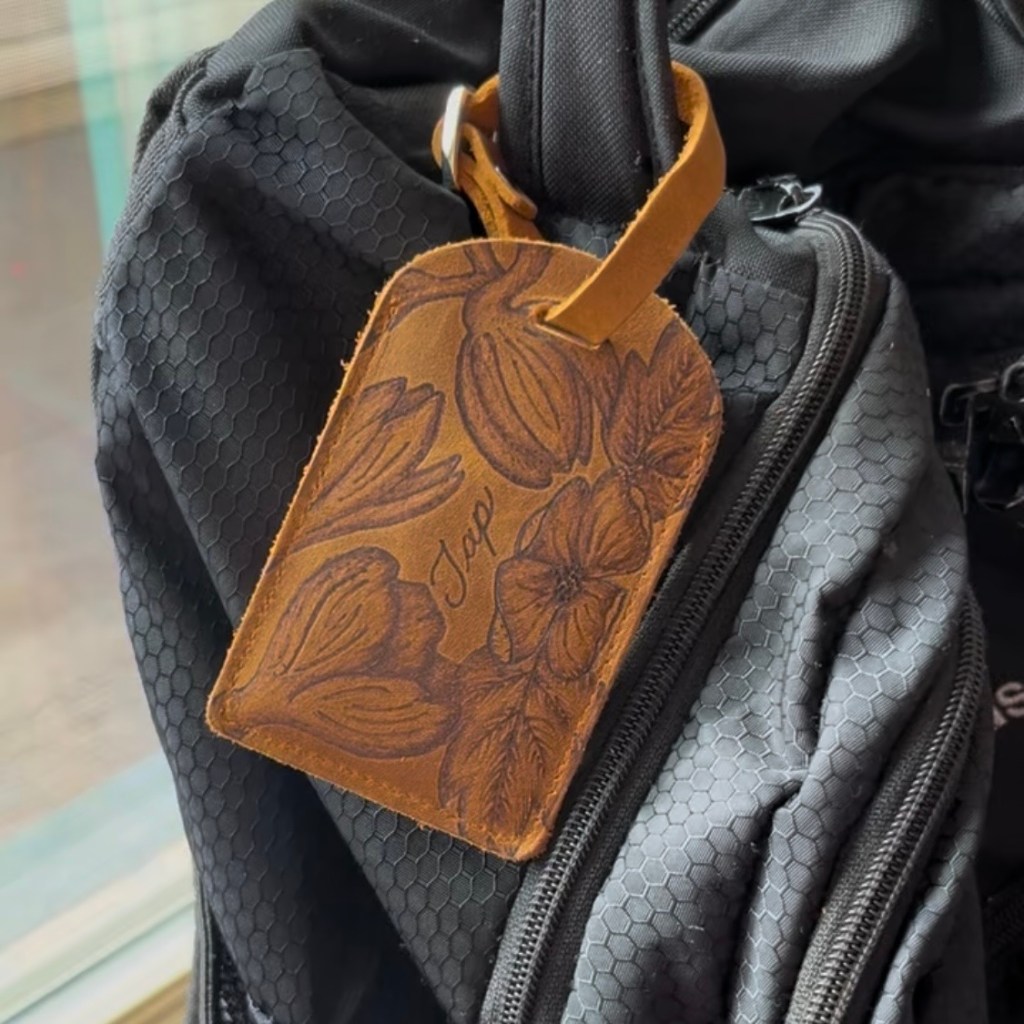 custom leather NFC business card holder with floral artwork and TAP design attached to backpack