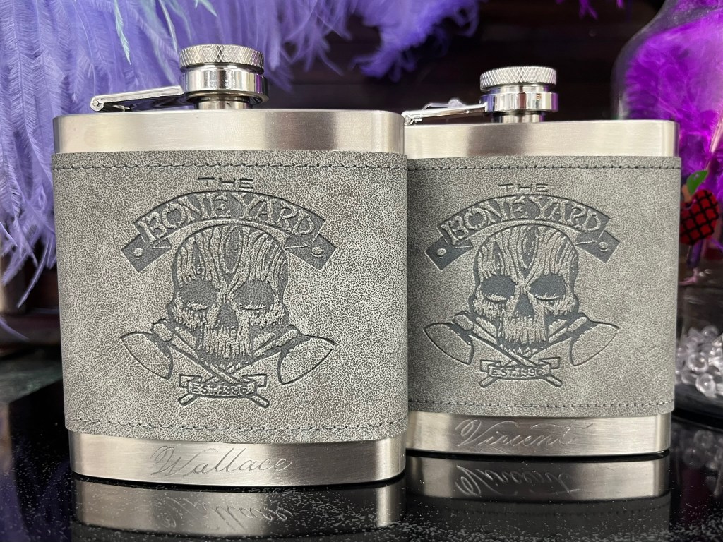 Two engraved stainless steel flasks with custom designs and names, showcasing personalized engraved flasks as Valentine’s Day gifts for men.