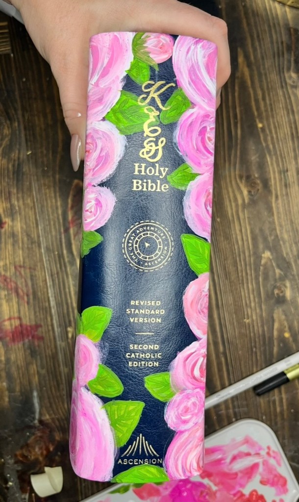 Hand-painted Bible spine with pink roses and gold initials personalized for First Communion