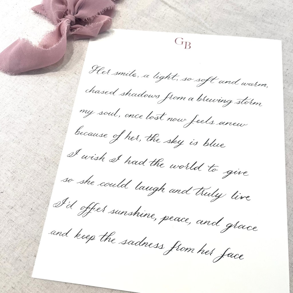 Formal script calligraphy written on a card showing an elegant, minimal lettering style for weddings and luxury events.