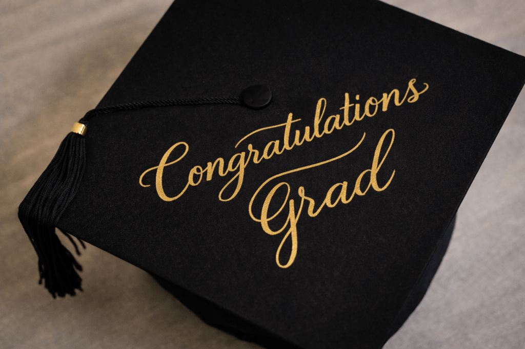 Graduation cap with handwritten Congratulations Grad in gold calligraphy