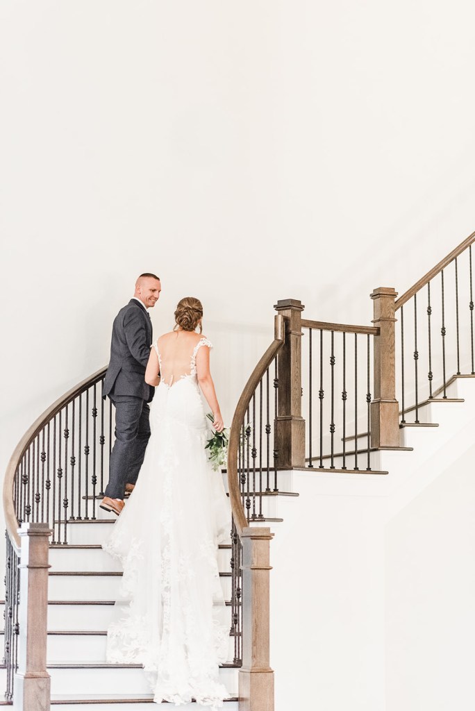 Bride and groom walking up staircase in minimalist wedding setting, demonstrating intentional design and space for guest connection.