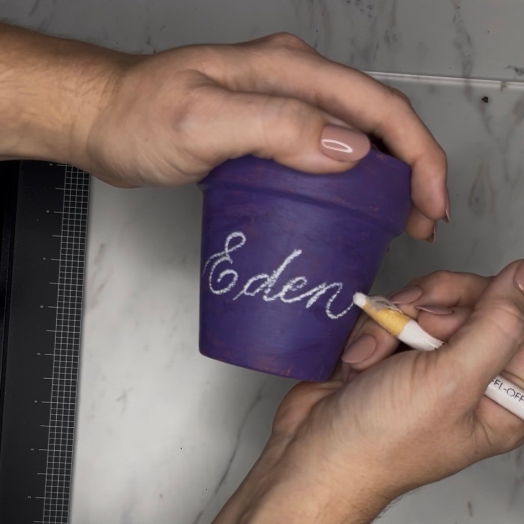 Houston calligrapher preparing terra cotta pot personalization with hand lettering for Earth Day event at Meridiana