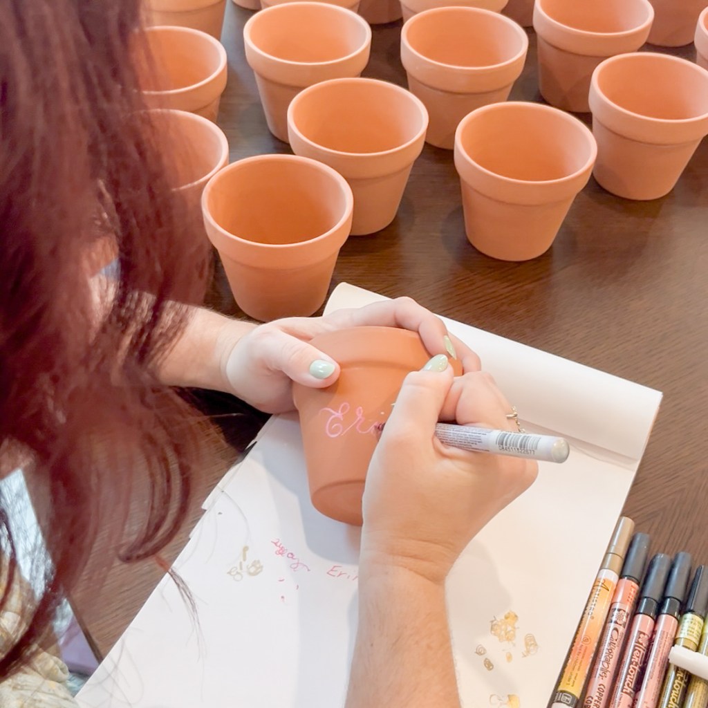 Close-up of live calligraphy writing a name on terra cotta pot at Houston event