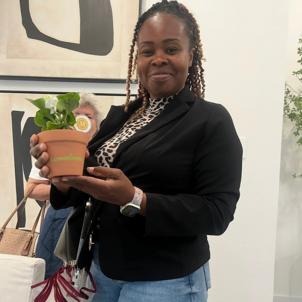 Woman holding personalized terra cotta pot with green and yellow calligraphy at Houston event
