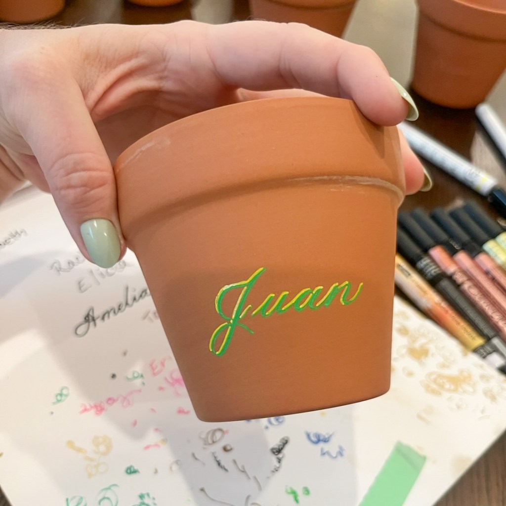 Colorful personalized terra cotta pot with green and yellow calligraphy lettering at live event