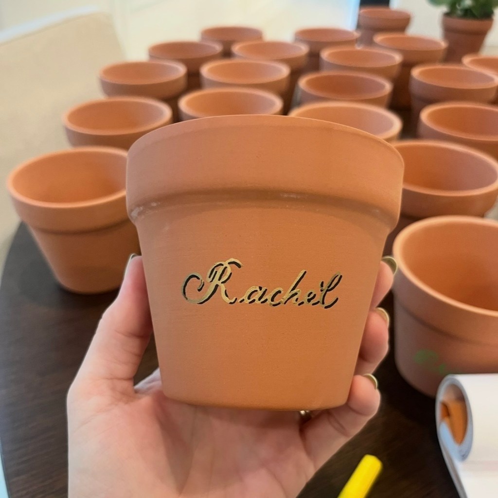 Personalized terra cotta pot with gold calligraphy and black shadow lettering at live event