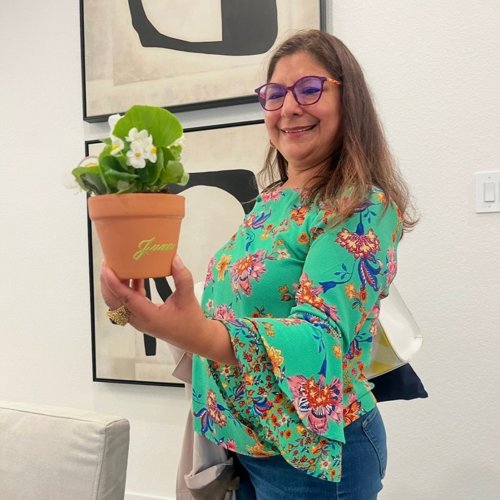 Woman holding personalized terra cotta pot with name Juan in green calligraphy at Houston live event