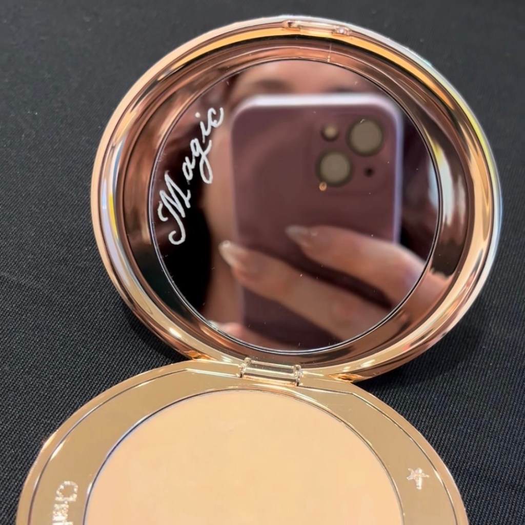 Hand-engraved Charlotte Tilbury compact mirror personalized with the word “Magic” during a live luxury beauty event.