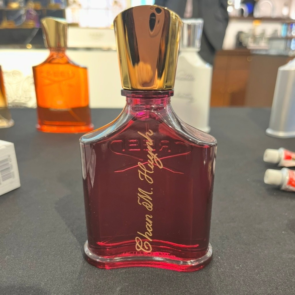 Hand-engraved perfume bottle personalized during a live luxury fragrance event with gold calligraphy lettering.