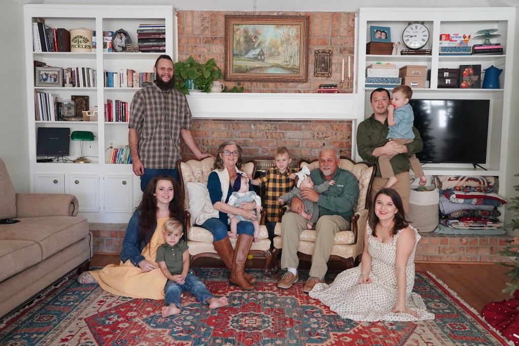 Three generations of family gathered together in a living room for a professional family portrait.
