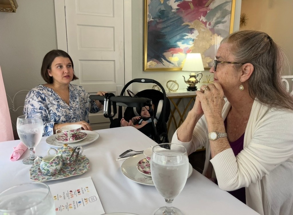 Mother and daughter talking together at a Mother's Day tea, sharing conversation and connection across generations.