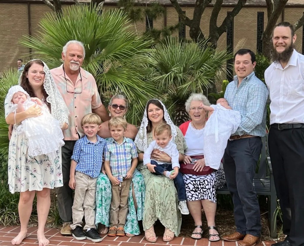 Multi-generational family portrait taken after a baptism celebration, including grandparents, parents, children, and grandchildren.
