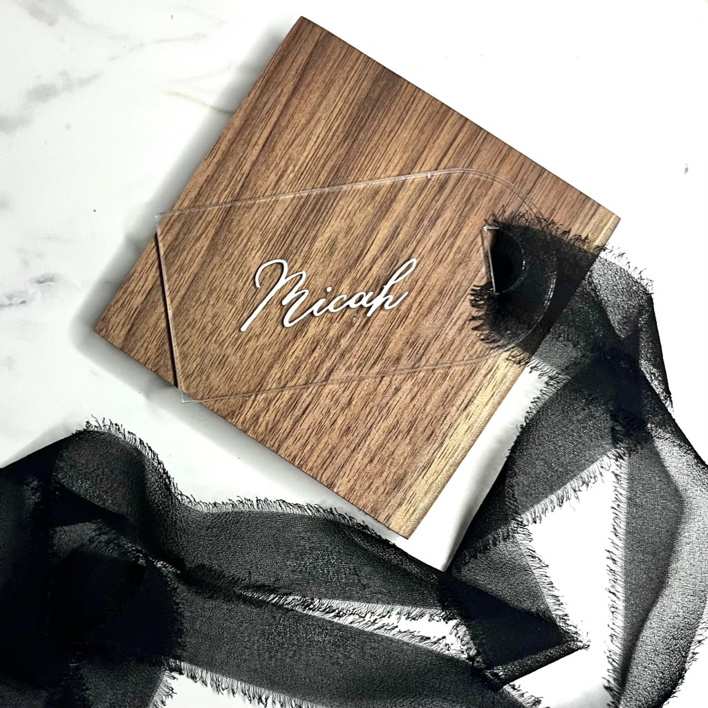 Custom acrylic wedding party gift tag with white calligraphy lettering and black chiffon ribbon for a groomsman.