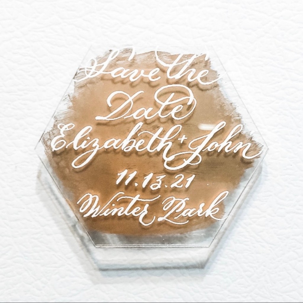 Early hand-lettered acrylic save-the-date magnet featuring white dip pen calligraphy and a gold painted background.