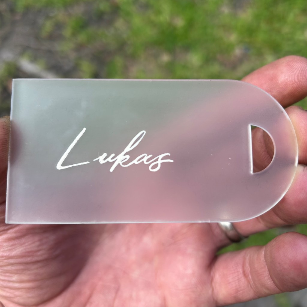 Custom acrylic wedding party gift tag with white calligraphy lettering that became cloudy after a clear coat application.