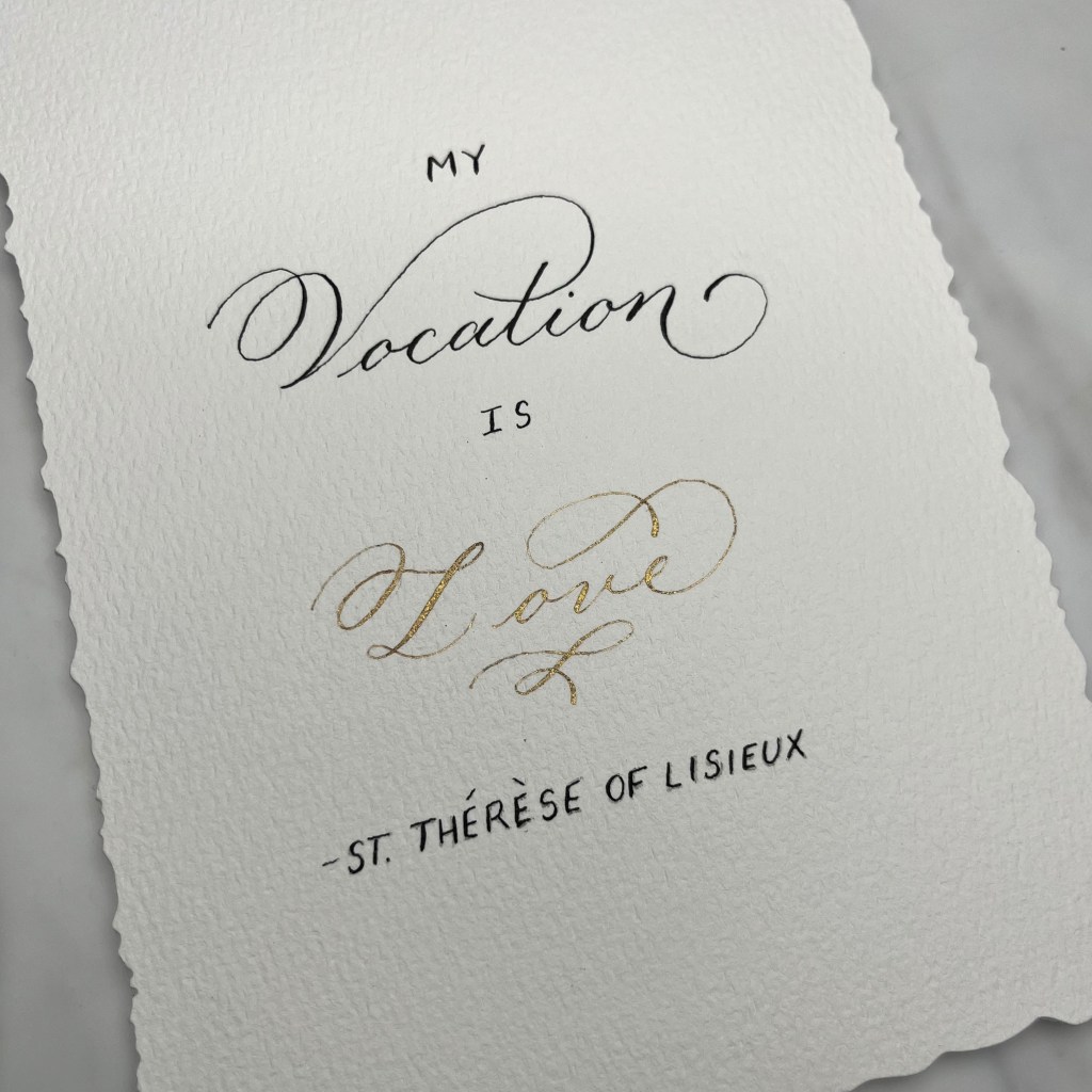 Hand-lettered calligraphy quote by Houston calligrapher Jessica Wofford featuring "My vocation is love" by St. Thérèse of Lisieux in black and gold ink on handmade paper.
