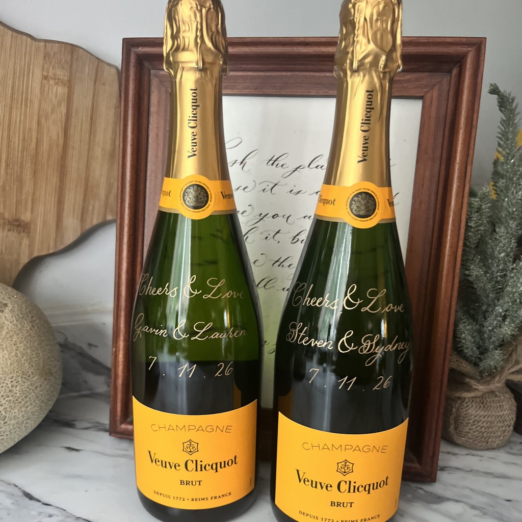 Personalized Veuve Clicquot champagne bottles engraved with couples’ names and dates as an example of a luxury realtor closing gift.