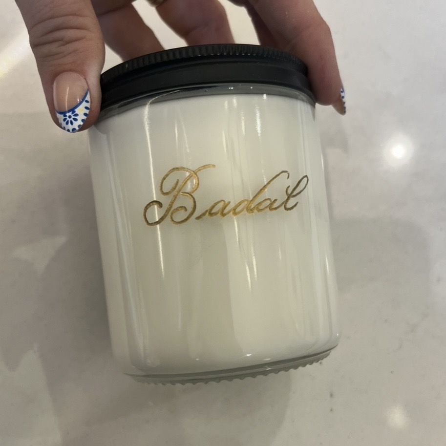 Custom Trilogy scented candle engraved with the name Badal in gold during a live personalization event at a Shea Homes grand opening in Conroe.
