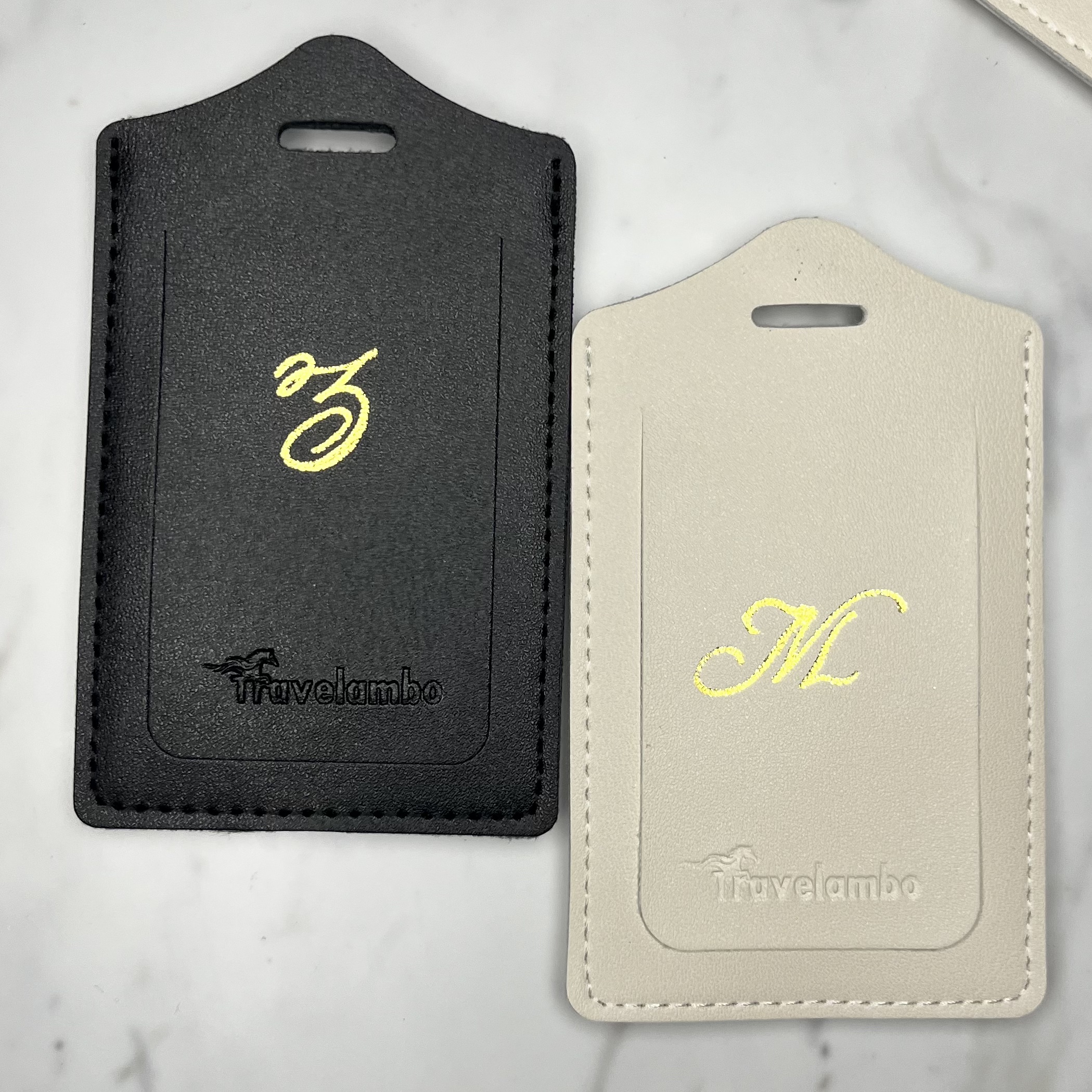 Black and white vegan leather luggage tags personalized with gold foil initials as an example of custom client gifts for realtors.